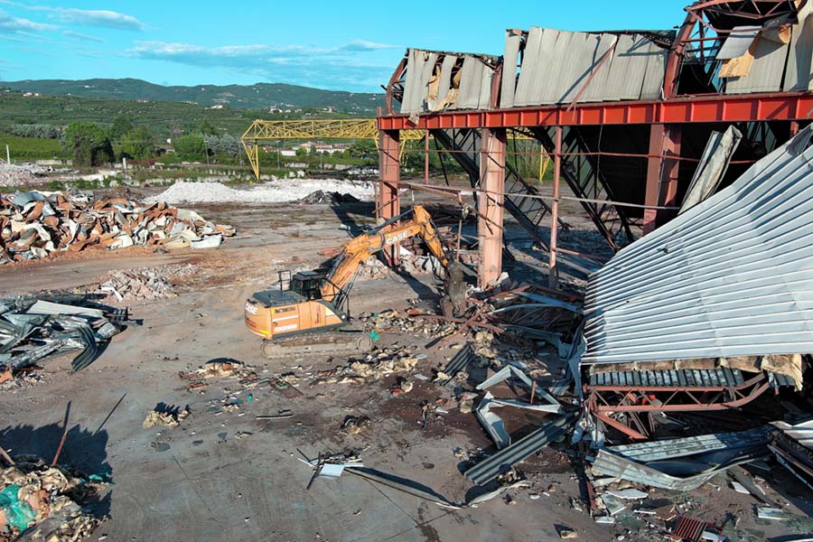 vista laterale del cingolato da demolizione accanto a dei detriti