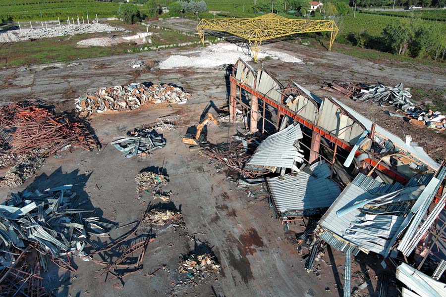 vista aerea del cingolato da demolizione accanto ad alcuni pezzi di lamiera